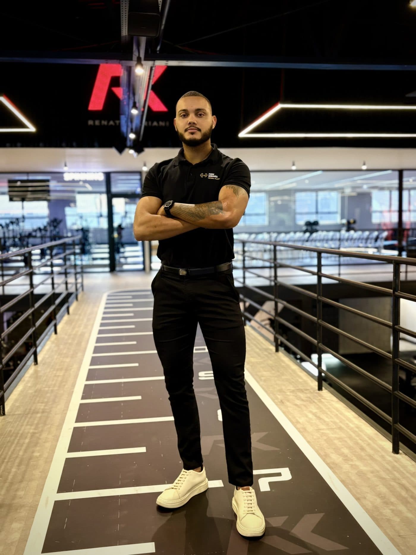 Pedro Guimarães em pé na academia, de braços cruzados
